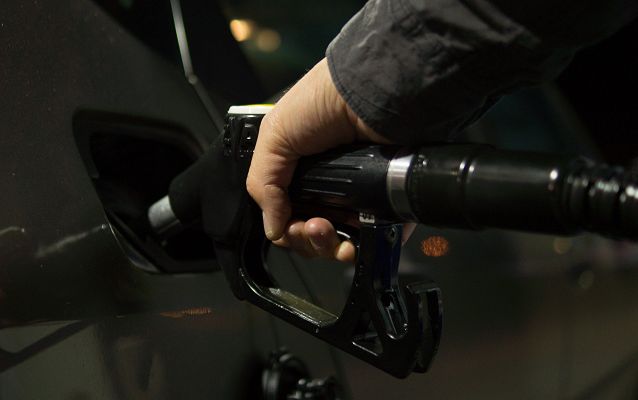 osoba trzyma pistolet paliwowy włożony do baku tankując samochód