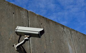 kamera monitoringu umieszczona na żelbetonowej ścianie. W tle niebieskie niebo.